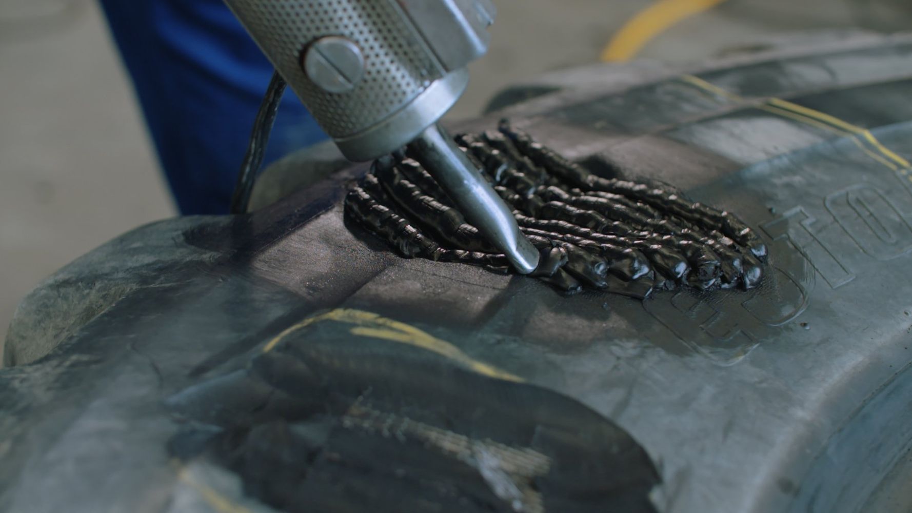 Auftragen des Rohgummi mit Extruder in vorbereitete Reparturstelle eines EM Reifen